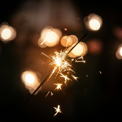 Das Hotel Karlwirt: herzlich willkommen! Funkelnder Wunderkerze-Lichtstrahl vor dunklem Hintergrund