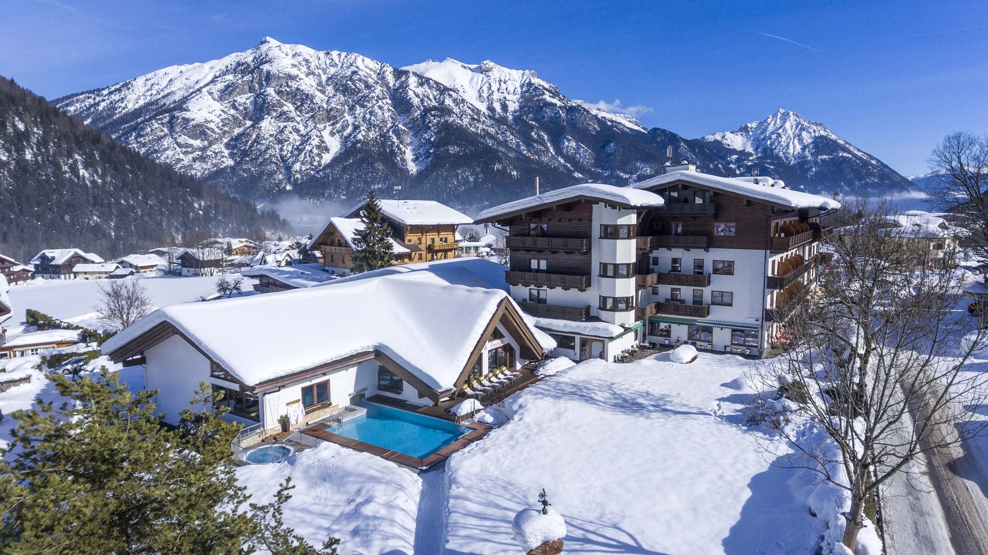 Das Hotel Karlwirt: herzlich willkommen! Winterliches Hotel mit schneebedecktem Außenschwimmbad in den Alpen