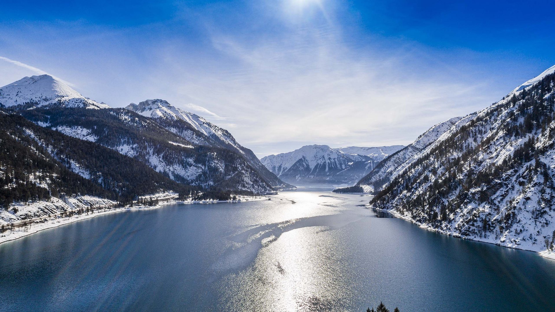 Skiing at Lake Achensee and more Mountain lake with snow-covered peaks and bright sunlight