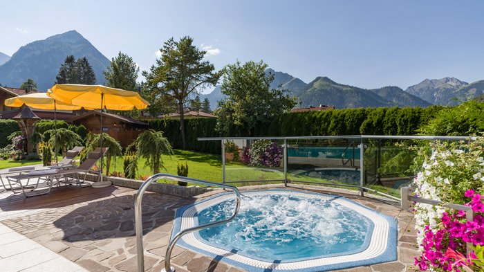 Das Hotel Karlwirt: herzlich willkommen! Whirlpool auf Terrasse mit Liegestühlen, Sonnenschirmen und Bergblick