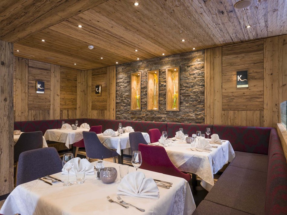 Das Hotel Karlwirt: herzlich willkommen! Elegantes Restaurant mit Holzwänden, gedeckten Tischen und modernem Dekor