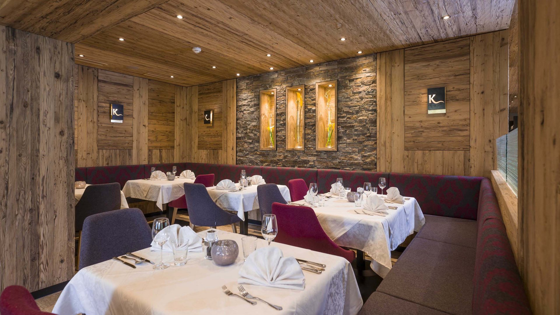 Das Hotel Karlwirt: herzlich willkommen! Elegantes Restaurant mit Holzwänden, gedeckten Tischen und modernem Dekor