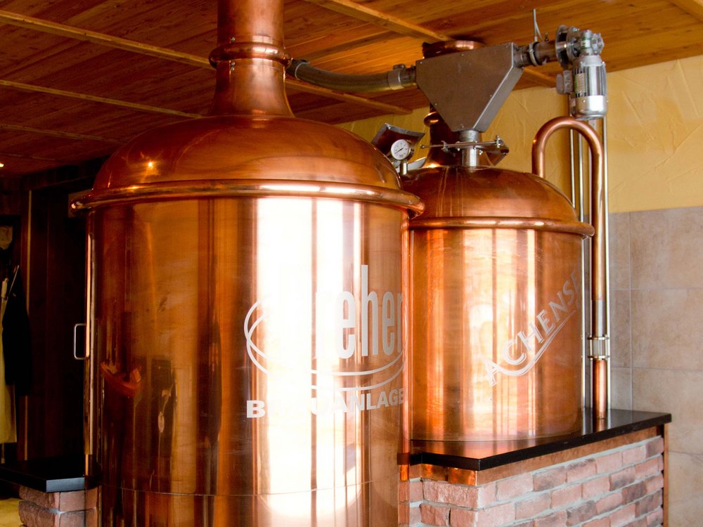 The Karlwirt’s Achenseebier Copper beer brewing system in a room with wooden ceiling and stone facade