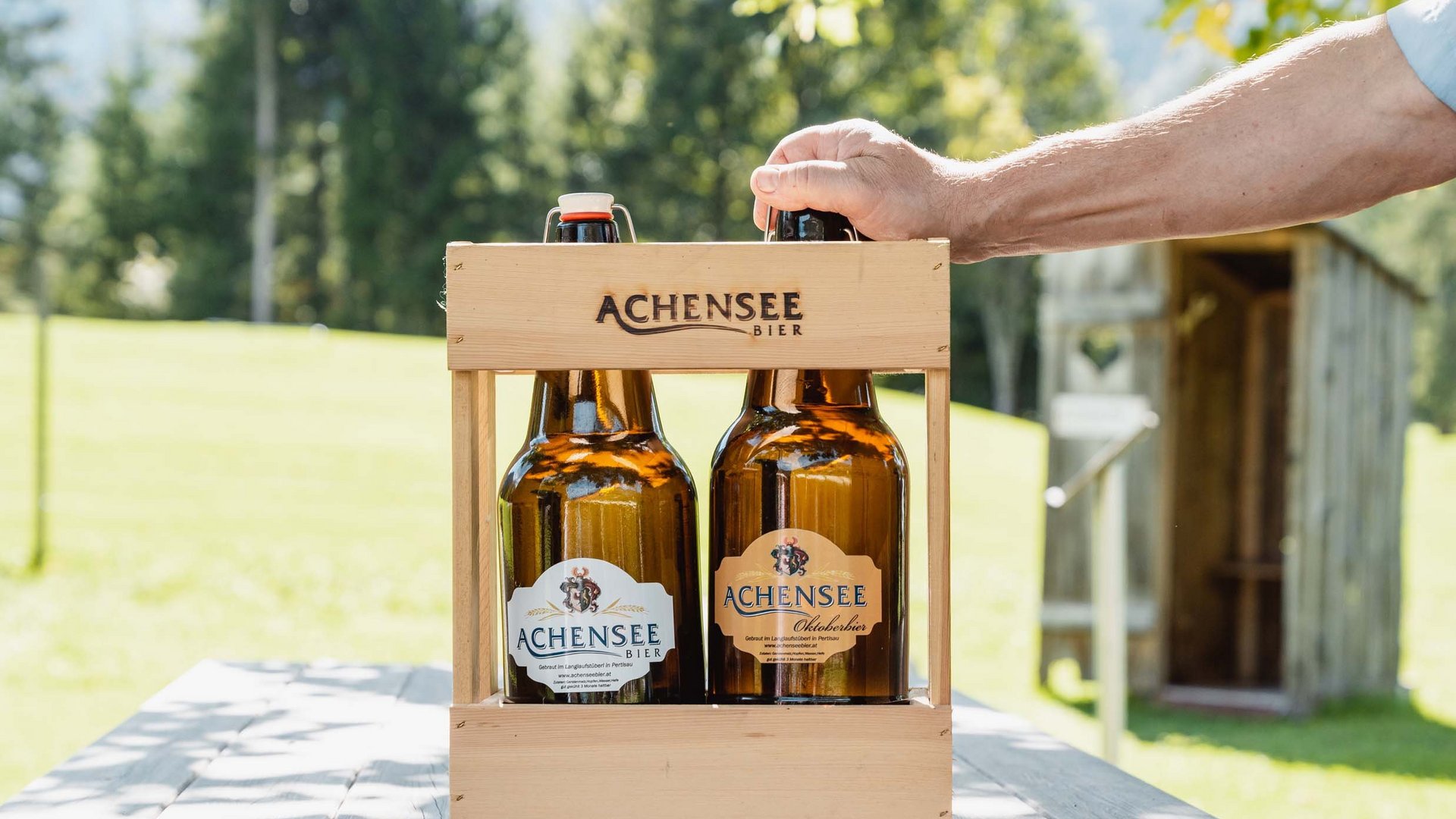 The Karlwirt’s Achenseebier Two bottles of Achensee beer in a wooden carrier on an outdoor wooden table