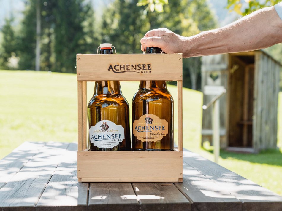The Karlwirt’s Achenseebier Two bottles of Achensee beer in a wooden carrier on an outdoor wooden table