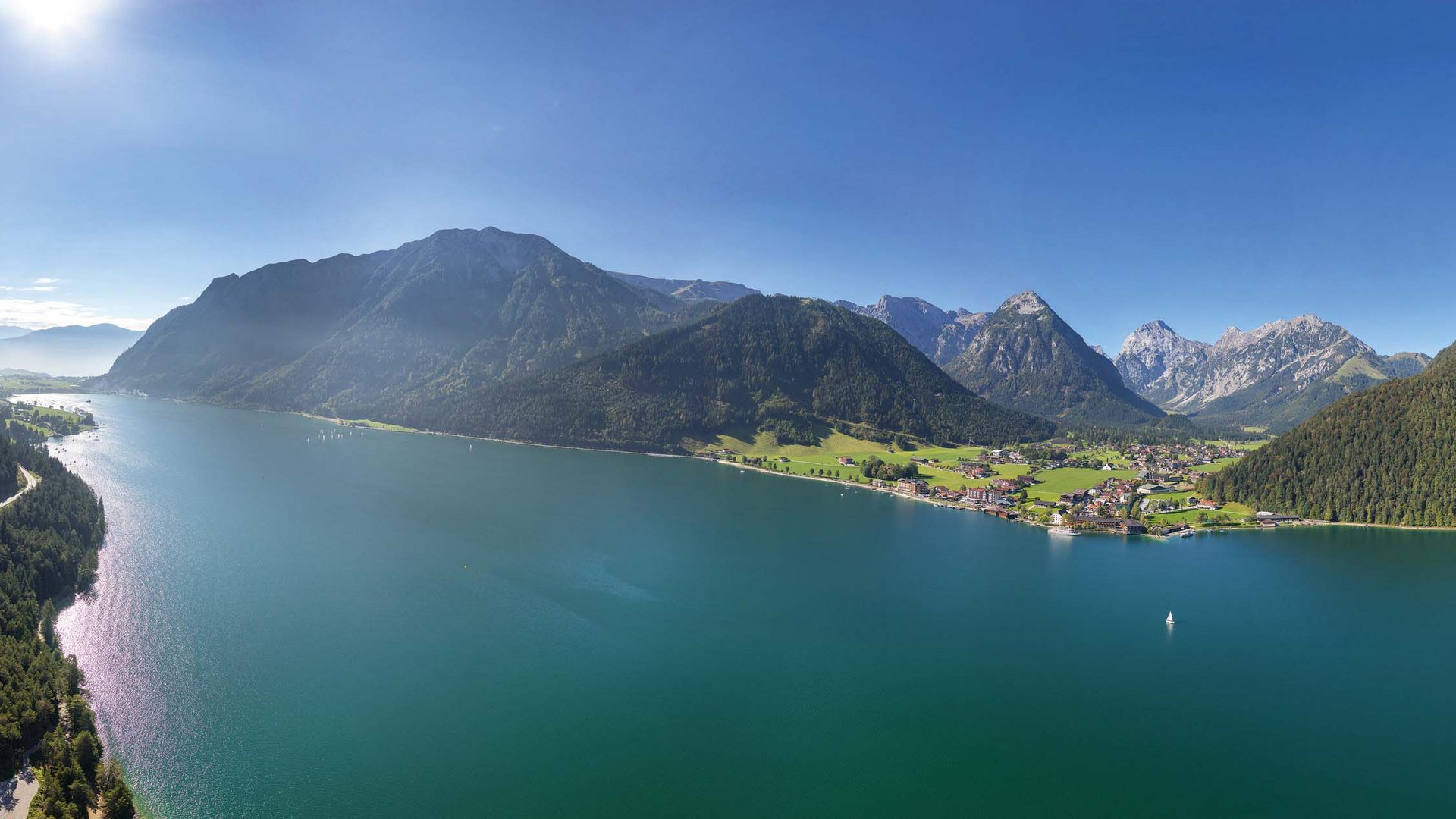Das Hotel Karlwirt: herzlich willkommen! Panoramablick auf einen See mit Bergen und Dörfern bei klarem Himmel
