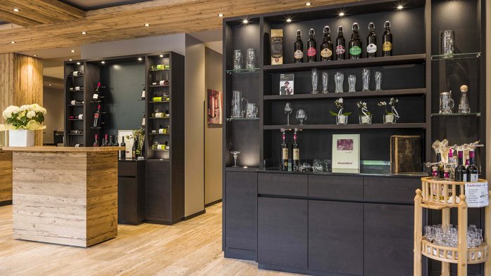 Das Hotel Karlwirt: herzlich willkommen! Elegante Bar mit Holztheke und Regalen voller Flaschen und Gläser