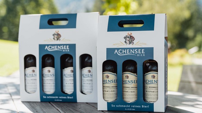 The Karlwirt’s Achenseebier Two packs of Achensee beer bottles on a wooden table outdoors